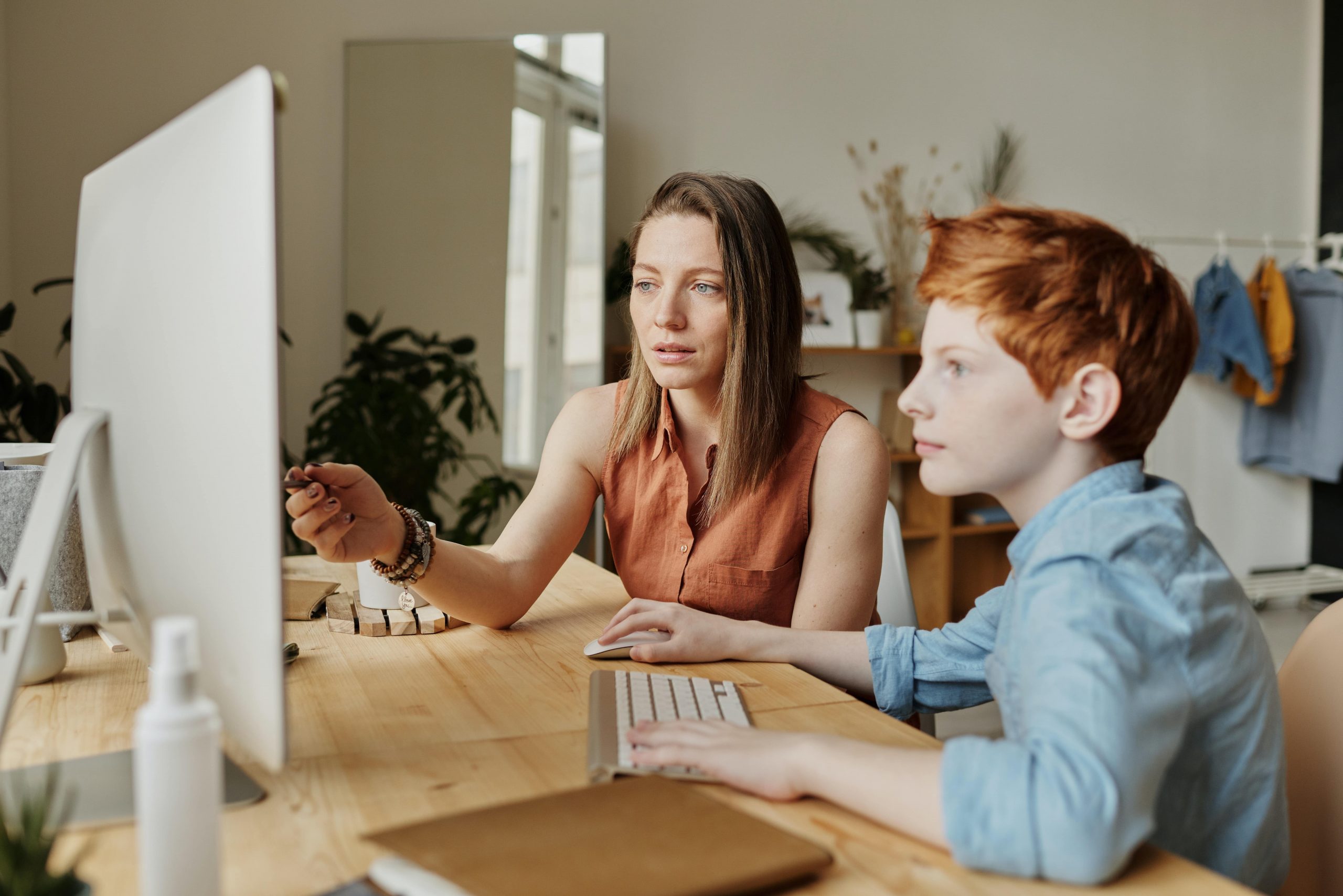 A mum and her son working on something together on the computer.